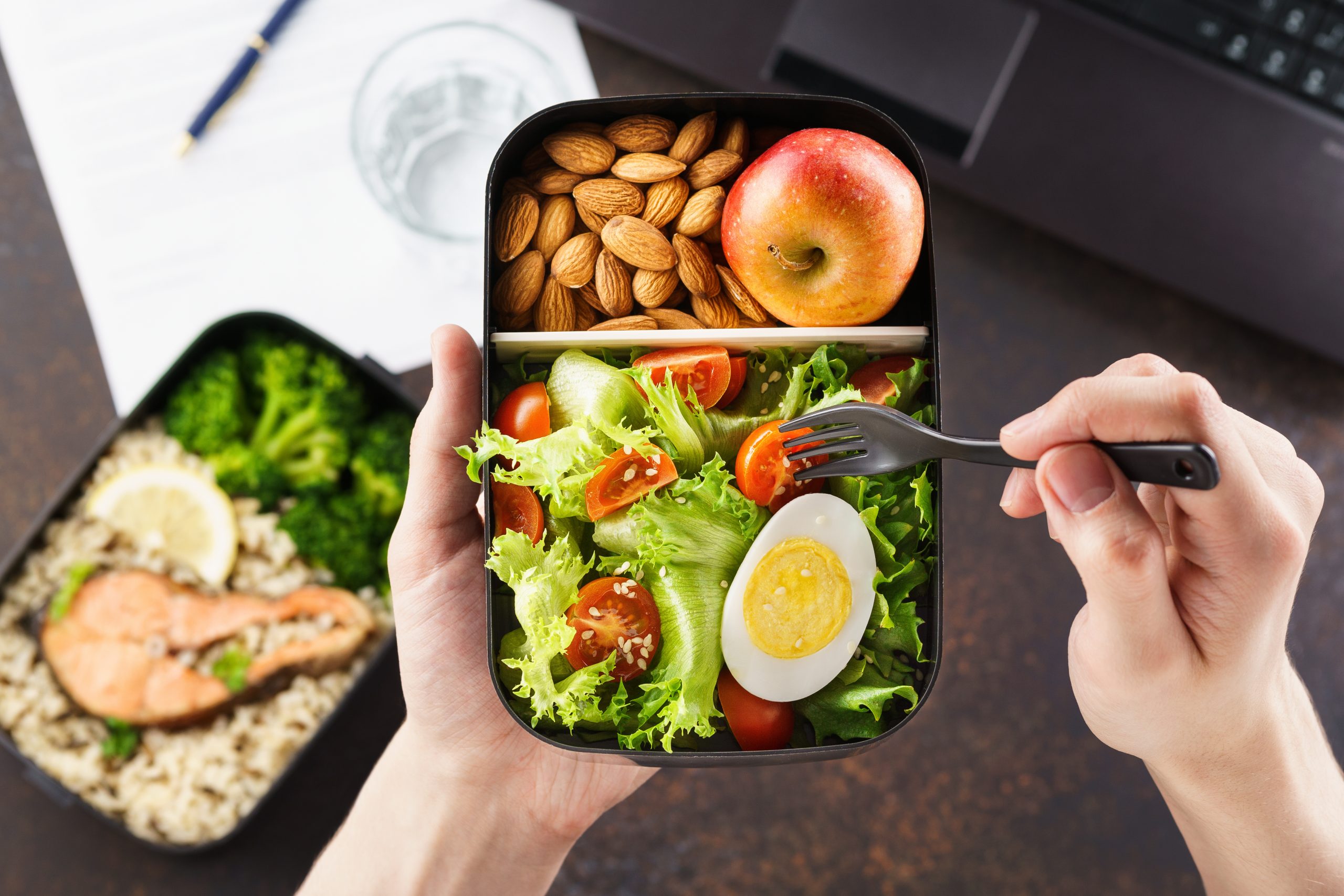 Man eating lunch from takeaway lunch box at working table.