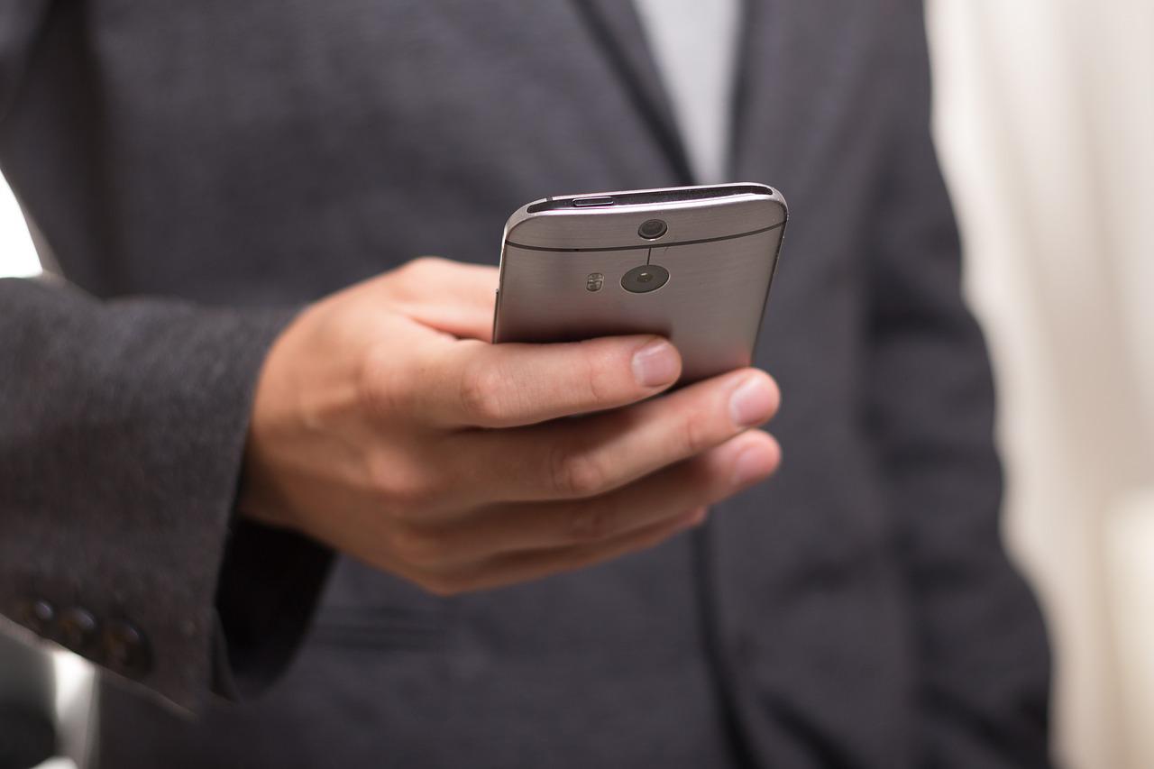 Mężczyzna w garniturze trzyma telefon z ostrzeżeniem od CyberRescue
